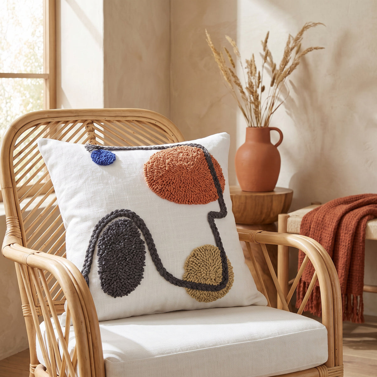 Rhea Tufted White and Rust Pillow in a room