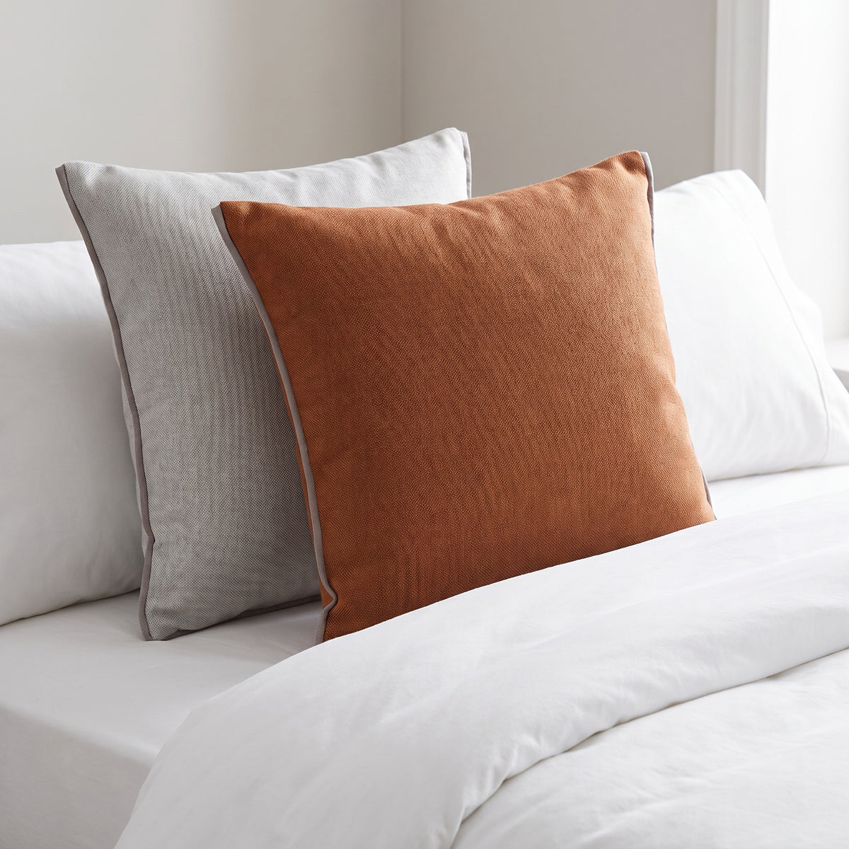Tova Textured Rust and Light Grey Pillow in a room